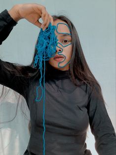 a woman with her hands on her head and blue yarn in front of her face