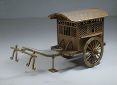 an old fashioned wooden cart with wheels and bars on the front, sitting on a white surface