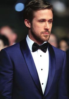 a man in a tuxedo and bow tie looking off to the side at an event