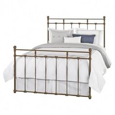 a metal bed frame with white sheets and pillows