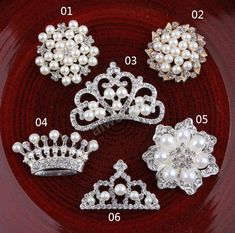 four tiaras and two brooches on a red plate, one with white pearls