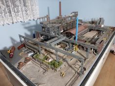 a model of a factory with workers and machinery on the floor in front of it