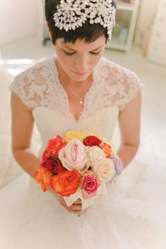 a woman in a wedding dress holding a bouquet with flowers on her head and wearing a tiara