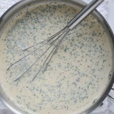 a pan filled with cream sauce and whisks on top of a white table