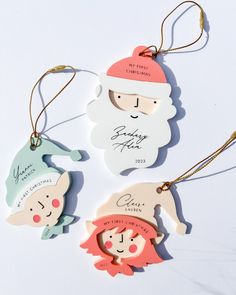 three personalized christmas ornament hanging from strings on a white surface with gold trim