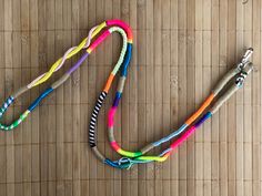 a multicolored lanyard is laying on a bamboo mat with a metal hook