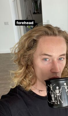 a woman drinking out of a coffee cup with skeletons on the mug in front of her