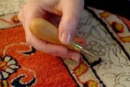 a person is using a small brush on a rug