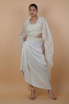 Off-white cape with floral, beads and thread embroidered border. Comes with a skirt and a top. - Aza Fashions Embroidered Draped Choli For Wedding, Wedding Embroidered Draped Choli, Wedding Choli With Draped Sleeves, Embroidered Draped Sets For Wedding, White Embroidered Dress With Cape Sleeves, White Lehenga With Traditional Drape For Evening, Festive White Dress With Cape Sleeves, White Fitted Set With Cape Sleeves, White Traditional Dress With Cape Sleeves