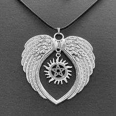 a silver necklace with an angel wing and pentagramil in the center on a black background