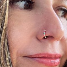 a close up of a woman with a nose ring on her nose and an ear piercing