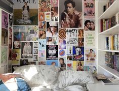 a room with many posters on the wall and a bed in front of it,