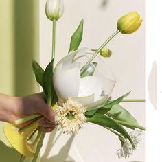 a person holding a vase with flowers in it and another hand reaching for the flower