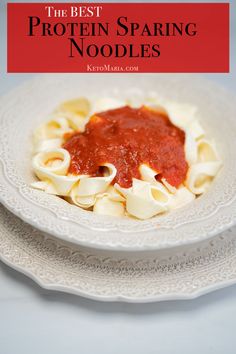 a white plate topped with pasta and sauce on top of a table next to a red sign