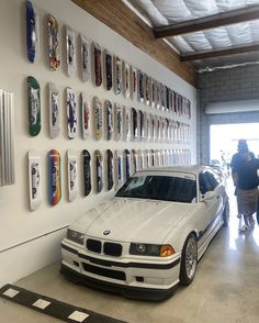 a white car parked in front of a wall with skateboards on it's sides