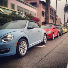 a row of cars parked on the side of a road next to palm trees and buildings