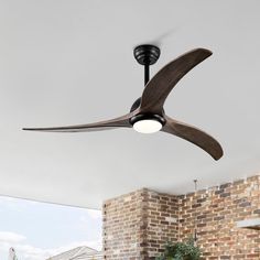 a ceiling fan that is hanging from the ceiling in a room with brick walls and windows