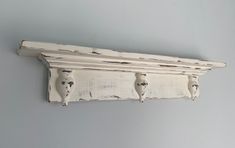 an old white painted shelf with three owls on it's sides and one is hanging from the wall