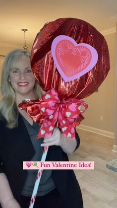 a woman holding a heart shaped lollipop in her hand and wrapped in foil