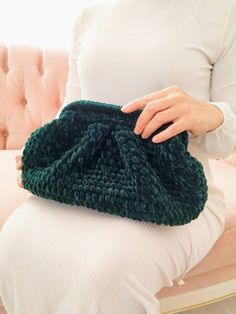 a woman sitting on a couch holding a green knitted purse