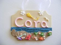 an ornament with the word cora on it and sea creatures in pink, blue, yellow and green