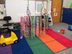 a room with colorful carpet and toys on the floor in front of whiteboard walls