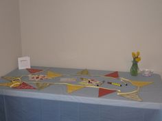 a blue table topped with lots of flags and bunting next to a vase filled with flowers