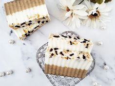 two pieces of soap sitting on top of a glass plate next to flowers and pearls