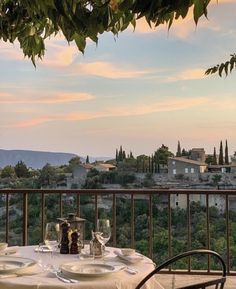 an outdoor dining area with table and chairs, overlooking the countryside at sunset or dawn