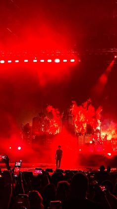 a man standing on top of a stage surrounded by red lights