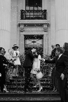 a bride and groom are kissing on the steps as confetti falls around them