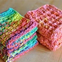 there are four pieces of colorful crocheted cloths on the table, and one is folded up