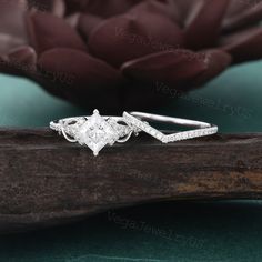 a diamond ring sitting on top of a piece of wood with flowers in the background