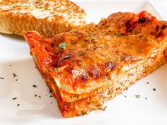 two slices of lasagna on a white plate with herbs sprinkled on top