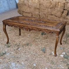 a wooden table sitting on top of dry grass