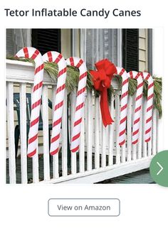 a white picket fence with candy canes tied to it and an ad for tetor inflatable candy canes