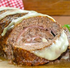 a meatloaf roll with cheese and sauce on it sitting on a cutting board