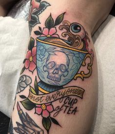 a woman with a tattoo on her arm has a cup of tea and a skull