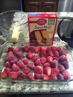 some strawberries are sitting on a counter next to a box of cake mix and a blender