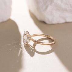 a diamond ring sitting on top of a table next to a white rock and stone wall