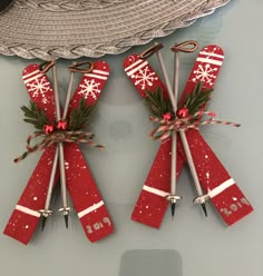 two red skis with bows and snowflakes are hanging from hooks on the wall