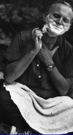 an old photo of a man shaving his face