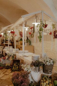 an outdoor market with lots of flowers and fruits in baskets on the tables, along with hanging lights