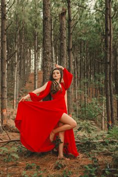 a woman in a red dress is sitting on the ground and posing for a photo