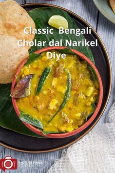 a bowl filled with curry next to bread on top of a wooden table, and the words classic bengali chola dal narkel diye