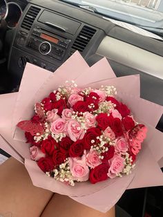 a bouquet of red and pink roses sitting on top of a car dashboard