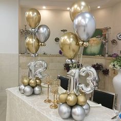 the table is set up with balloons and silver and gold decorations for an anniversary celebration