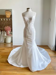 a white wedding dress on display in front of a mannequin's head