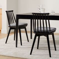 a black table with two chairs and a white rug on the floor in front of it