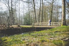 a man and woman standing on a bridge in the woods